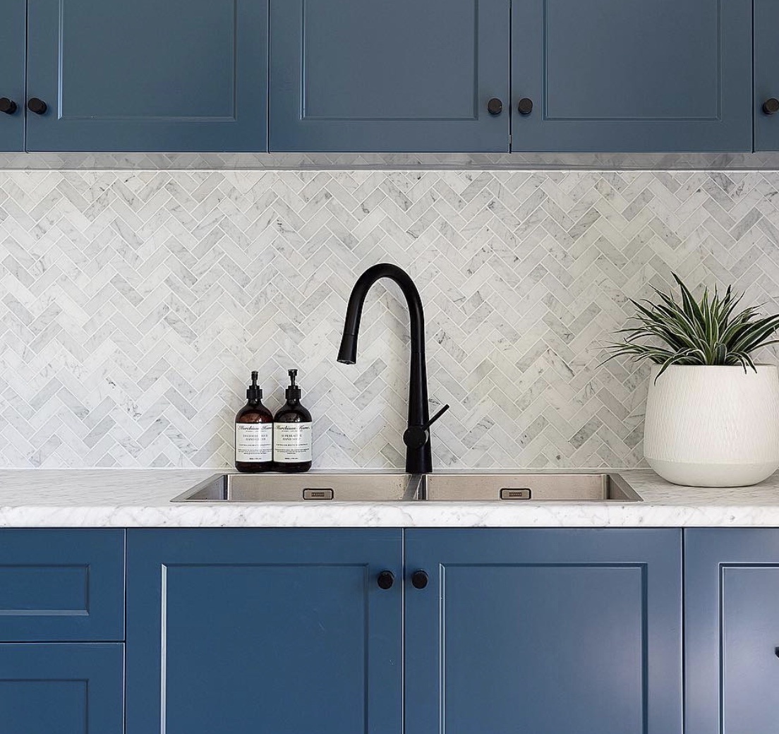 A white marble herringbone tile creates a clean aesthetic in a modern ...