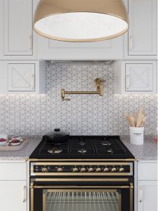 marble pattern backsplash tiles with brass oven hood accent